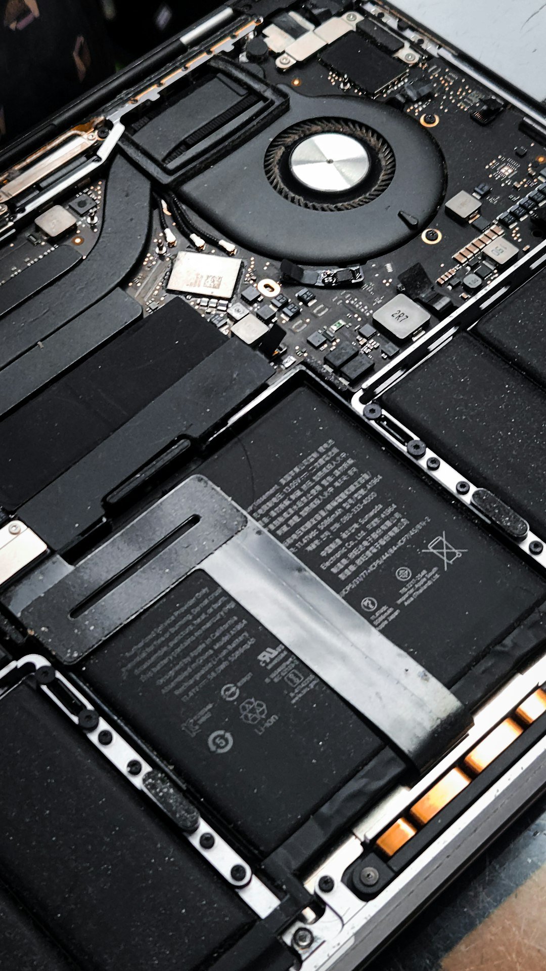 Internal view of a MacBook Pro showing the cooling fan logic board, highlighting electronic components power management chips and thermal design inside a modern laptop.